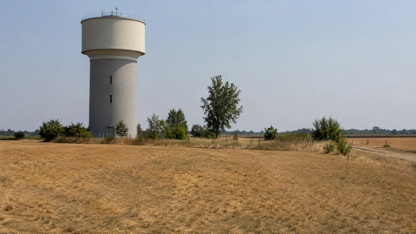 Wasserturm eines Wasserwerks an einem ausgedörrten Feld bei Sommerhitze